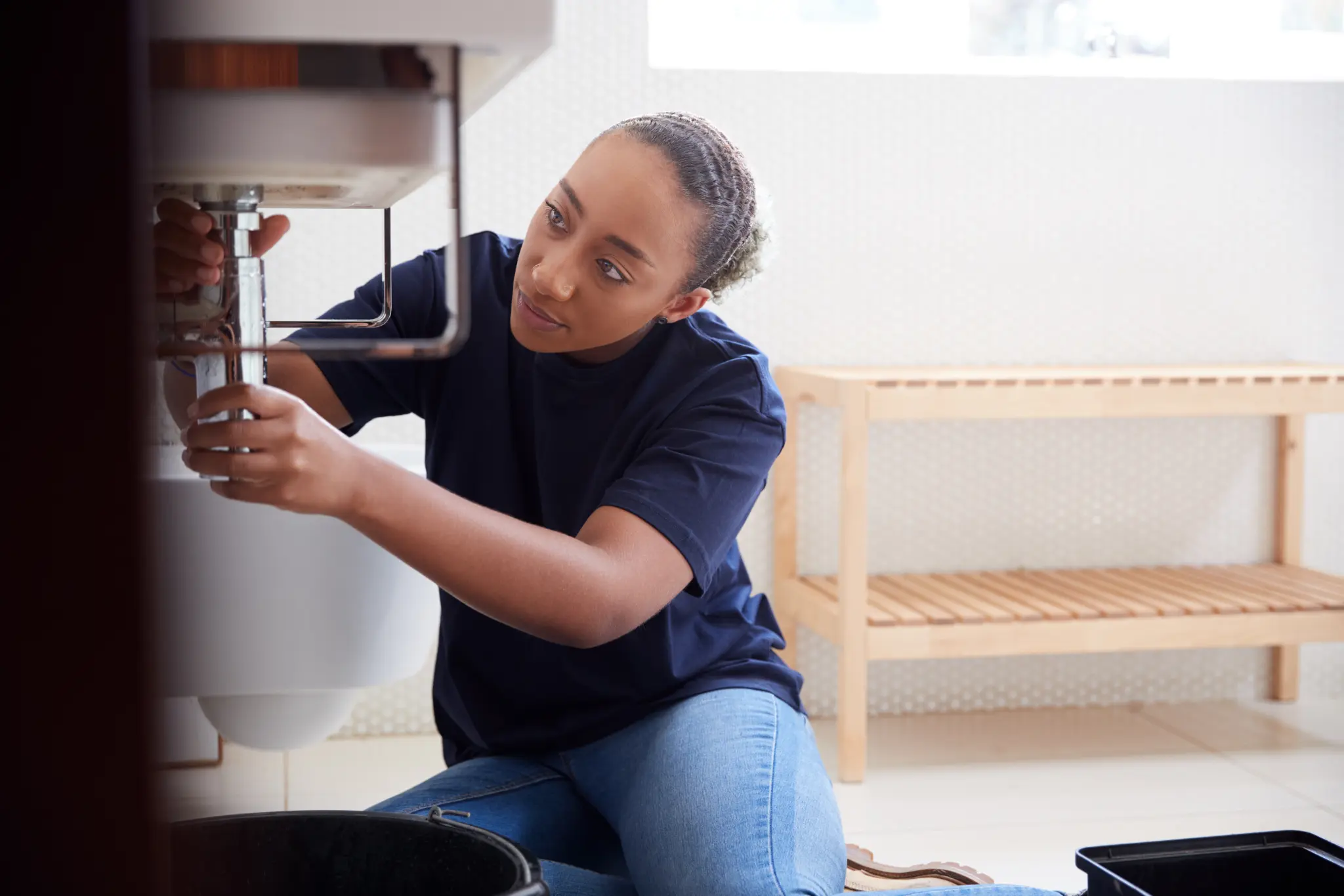 Female plumber fixing leaking sink